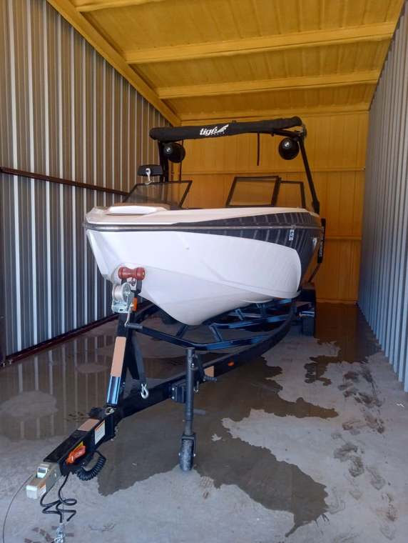 Wake boat on a trailer inside a metal storage building